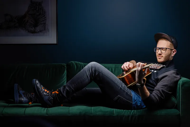 Isaac playing guitar on the green couch
